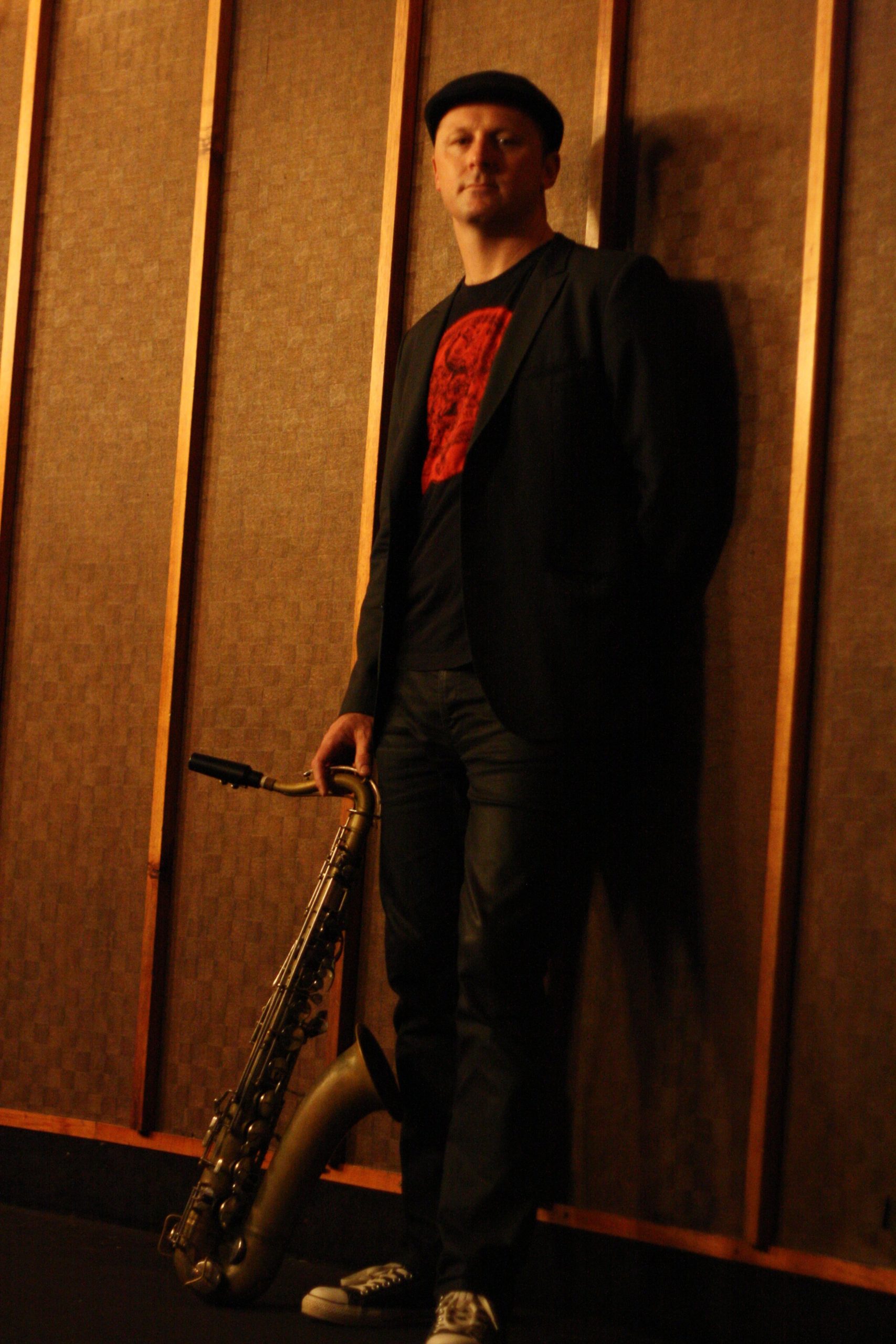 Jamie Oehlers with saxophone in a studio setting